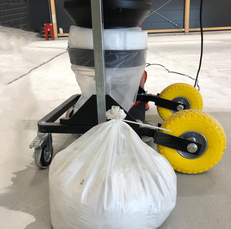 Close-up of a Depureco vacuum with a Longopac® endless bag; tied-off section and filled dust bag on the floor beside yellow wheels.