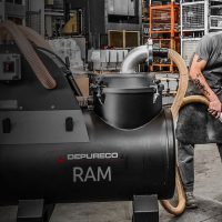 Machinist using Depureco RAM sump vacuum to clean CNC coolant tank, recover coolant, and extract chips and swarf.