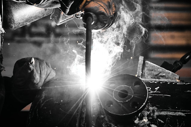 Welder producing sparks and metal fume in a fabrication shop