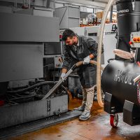 Machinist cleaning CNC coolant tank with Depureco RAM sump vacuum — coolant recovery and chip filtration system.